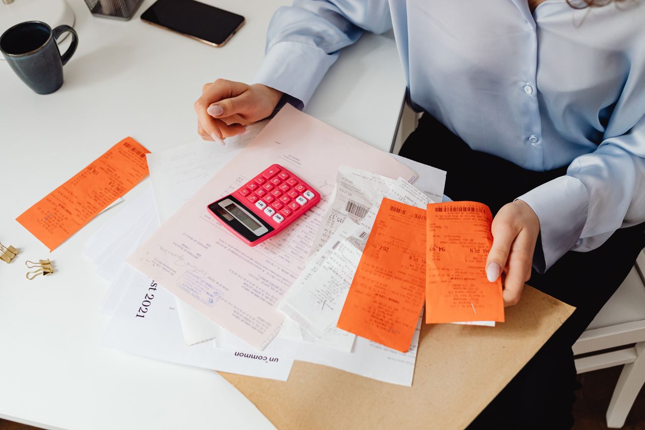 Person holding receipts and using a calculator to track taxes on extra money made from home