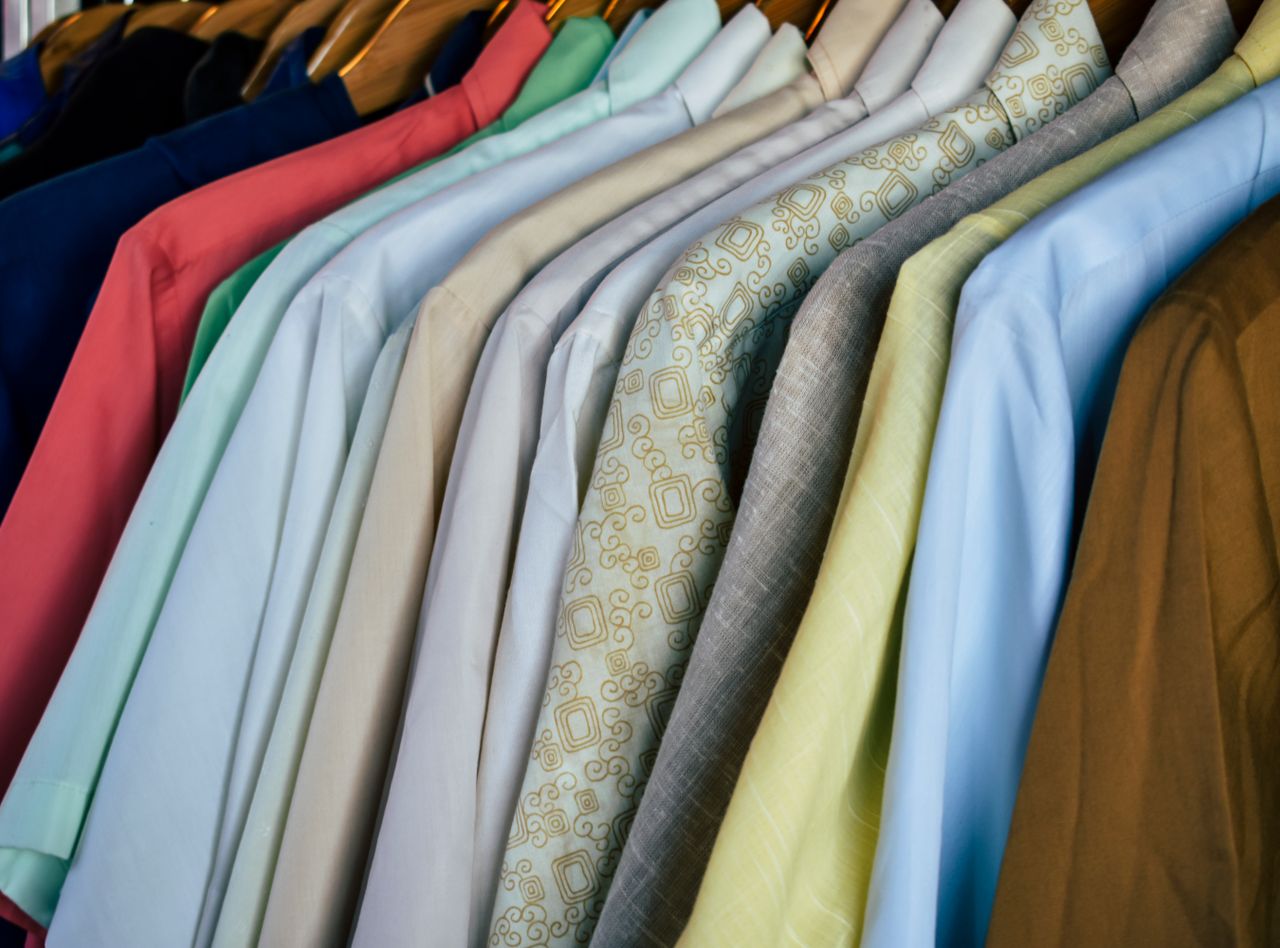 Shirts in many colors and fabrics on wooden hangers, showing color choices for men's outfits