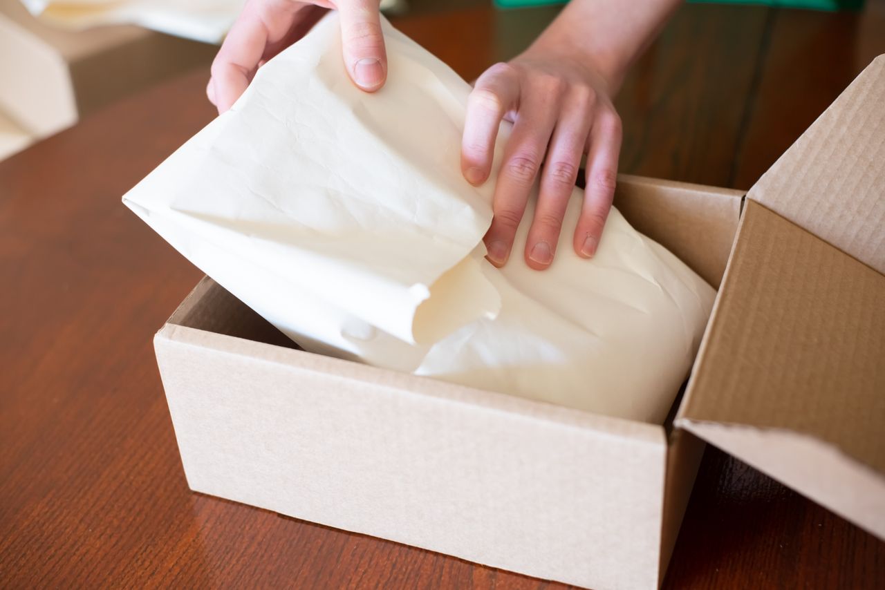 Person packing an order into a cardboard box after setting up an online store