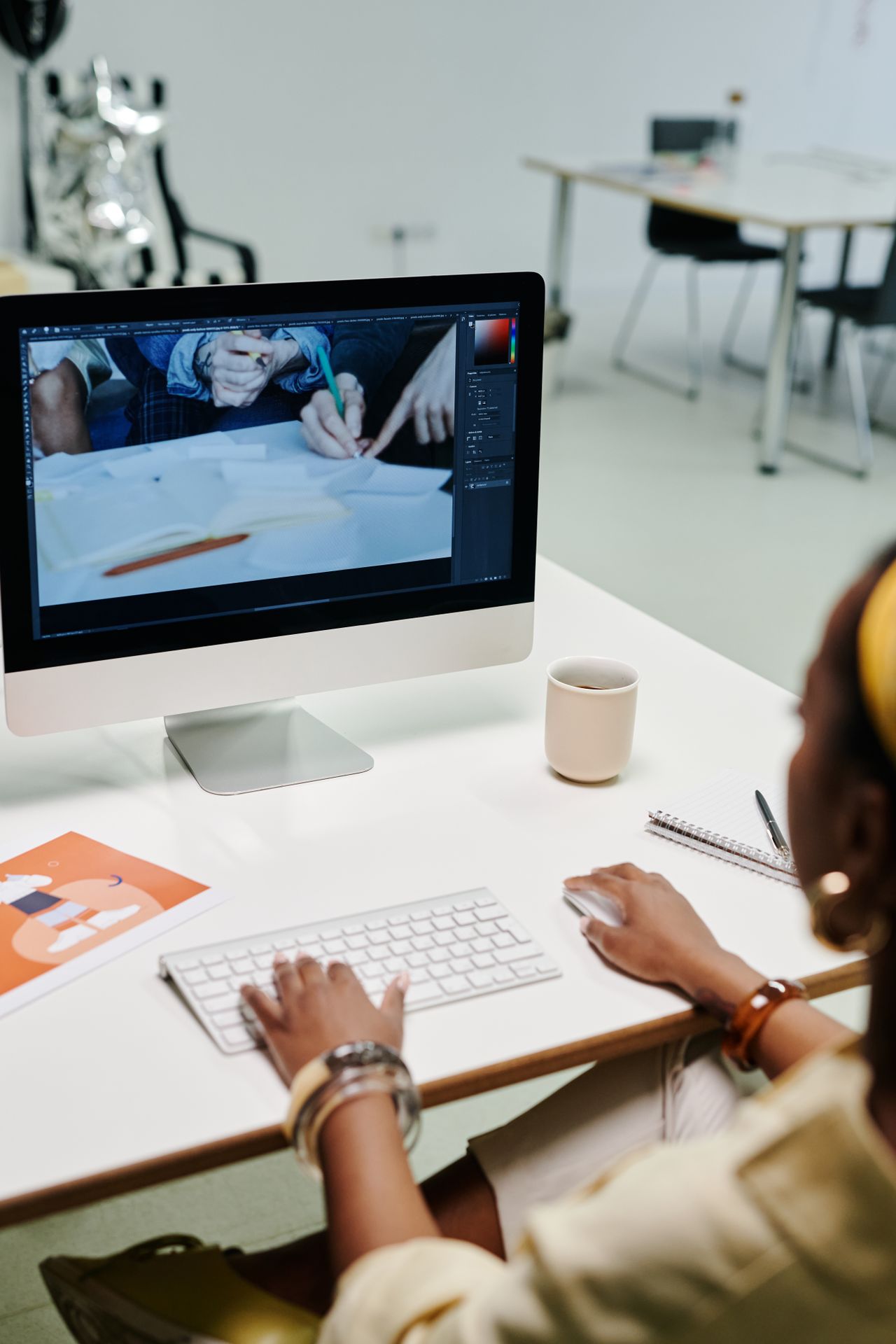 Designer working on a desktop Mac in an office, preparing posts to publish from Instagram on a computer
