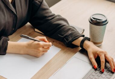 Writer typing on a laptop with pen in hand, working on ways to make money writing online