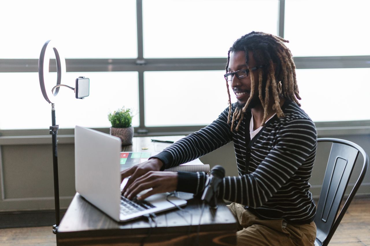 Creator working on a laptop with a ring light and microphone while managing a Sellfy store