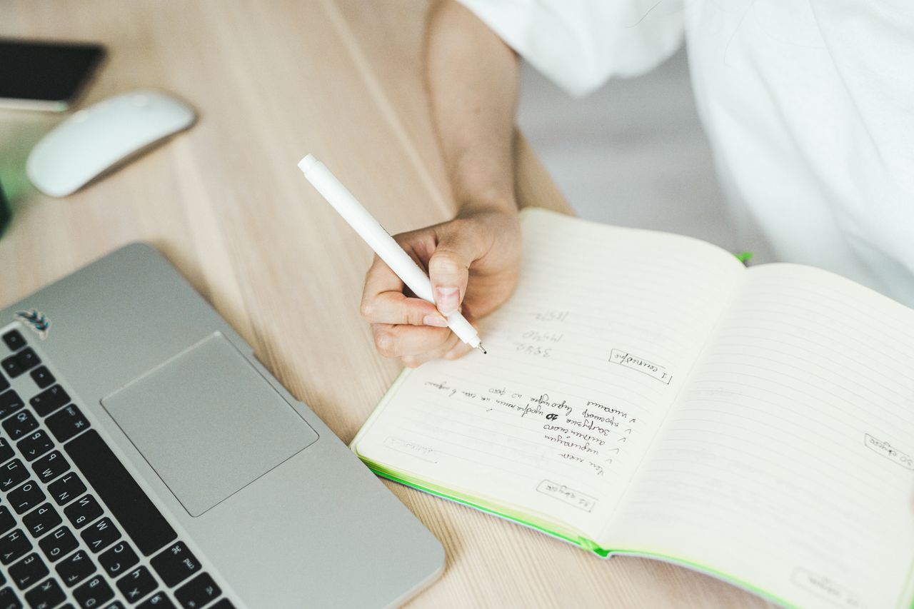 Person writing in a notebook to fact-check how to make money online tips from Quora