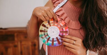 Woman holding a color wheel to choose shades, the same job an HTML color picker does on screen