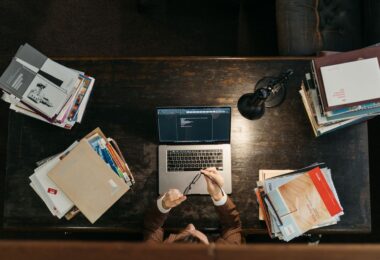 Student at a wooden desk with books and a laptop, searching for online jobs without investment from home
